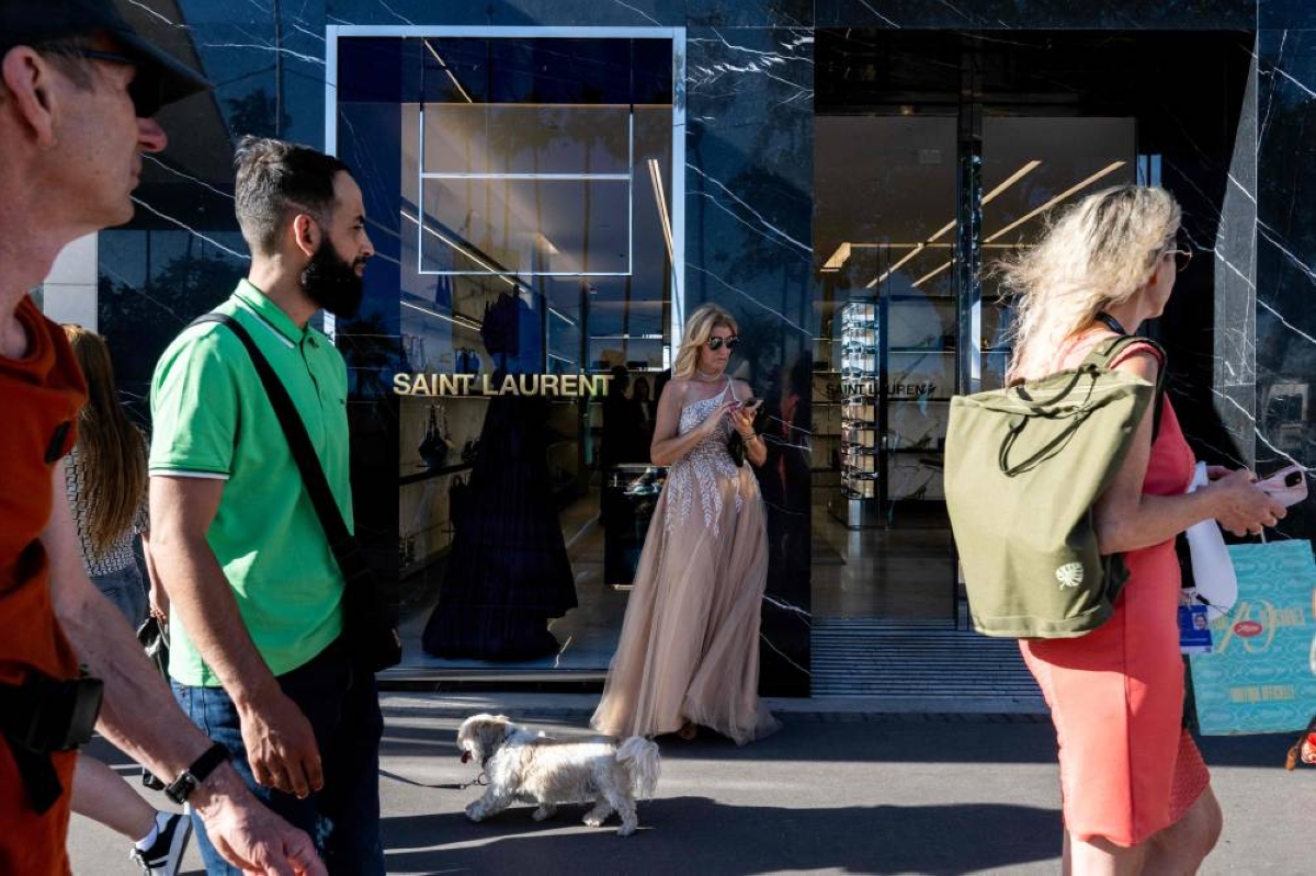 A woman in evening attire stands in front of a Yves Saint Laurent shop during the official ceremony on the sidelines of the 79th edition of the Cannes Film Festival in Cannes, southern France, on May 12, 2026. (Photo by Anna KURTH / AFP)