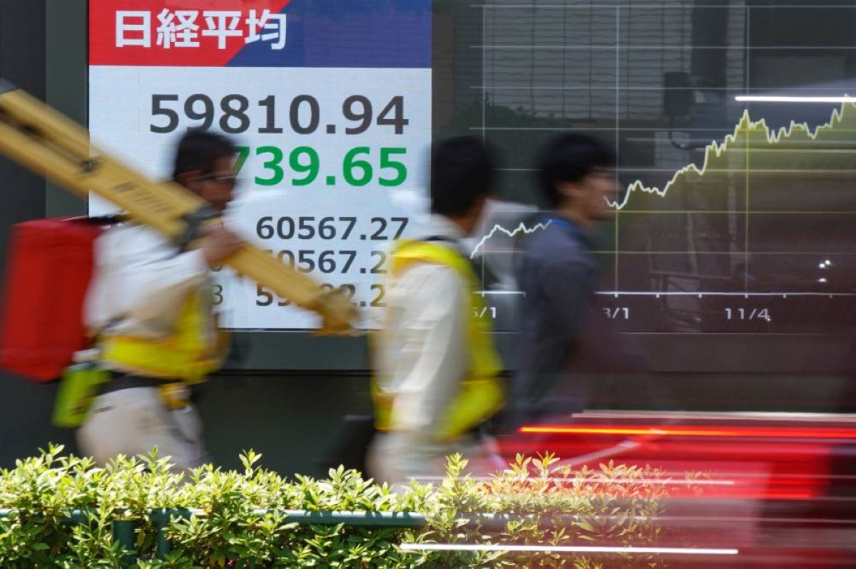 Passersby walk in front of an electronic quotation board displaying stock prices along a street in Tokyo. The Nikkei 225 closed down 1.2% to 59,804.41 points Wednesday.