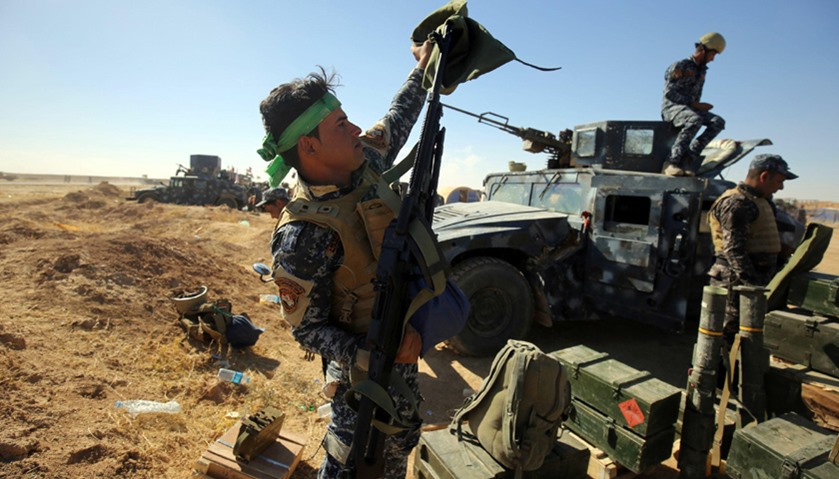 An Iraqi policeman inspects his weapon at the Qayyarah military base