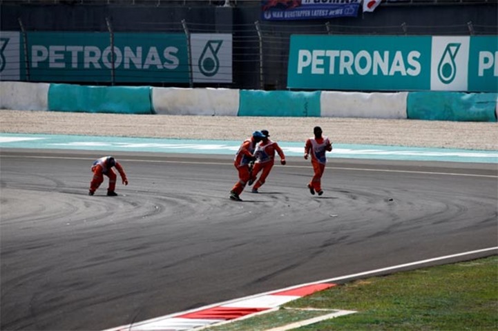 Track marshals collect debris from the track after Mercedes\' Nico Rosberg crashed during the race