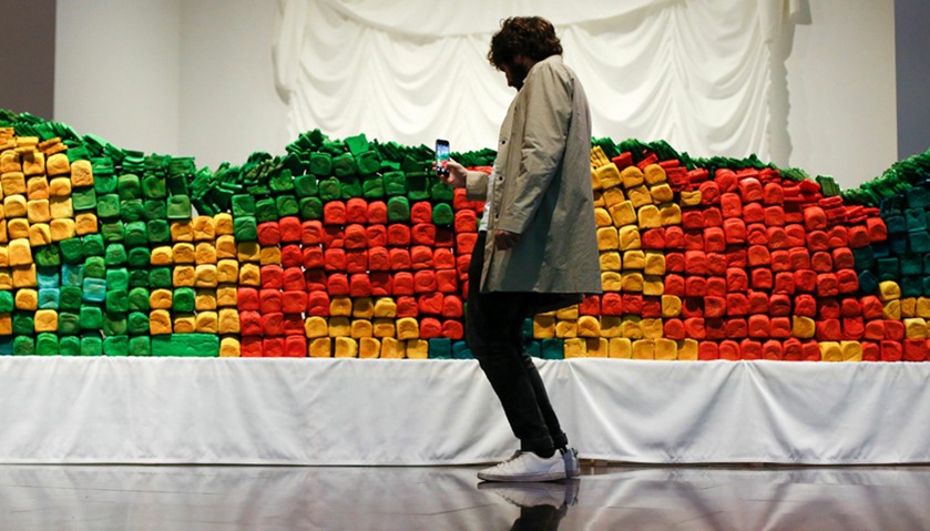 A man takes a photo of the installation \"Breadline\" by Spanish artist Antoni Miralda