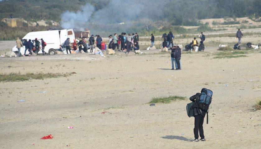 Migrants, carrying their luggage, leave the \"Jungle\" migrant camp