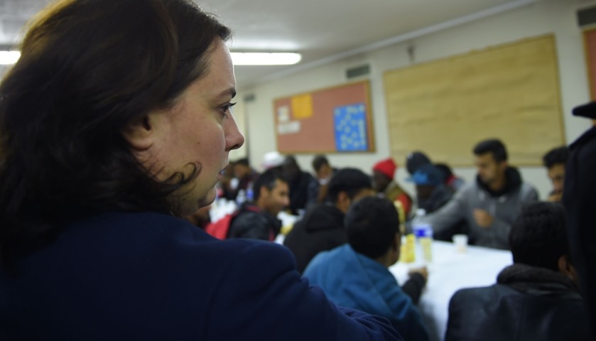 French Housing Minister Emmanuelle Cosse looks on as migrants processed at an orientation centre