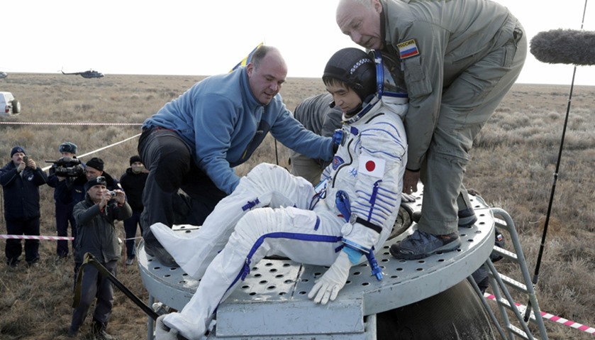 Ground personnel help ISS crew member Japanese astronaut Takuya Onishi to get out