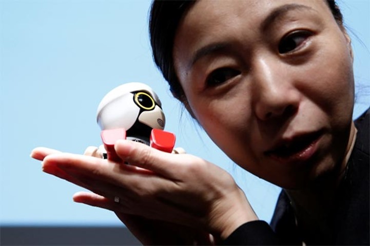 A staff member listens Kirobo Mini\'s voice as she poses with the robot in Tokyo