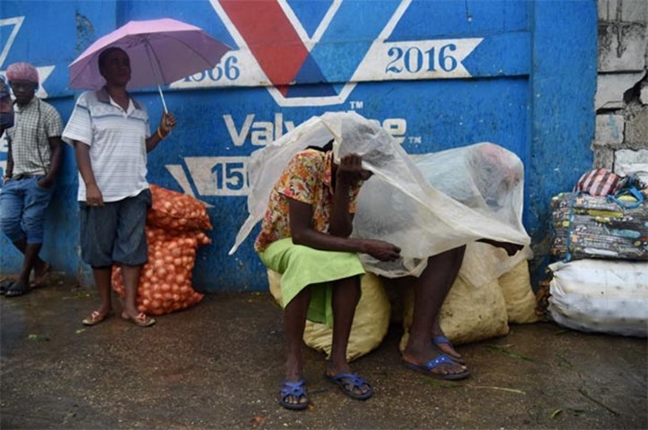 Women protect themselves from the rain with plastic in the Haitian capital of Port-au-Prince