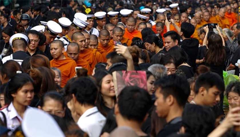 Well-wishers offer alms to Buddhist monks to mark the first anniversary of the king’s death