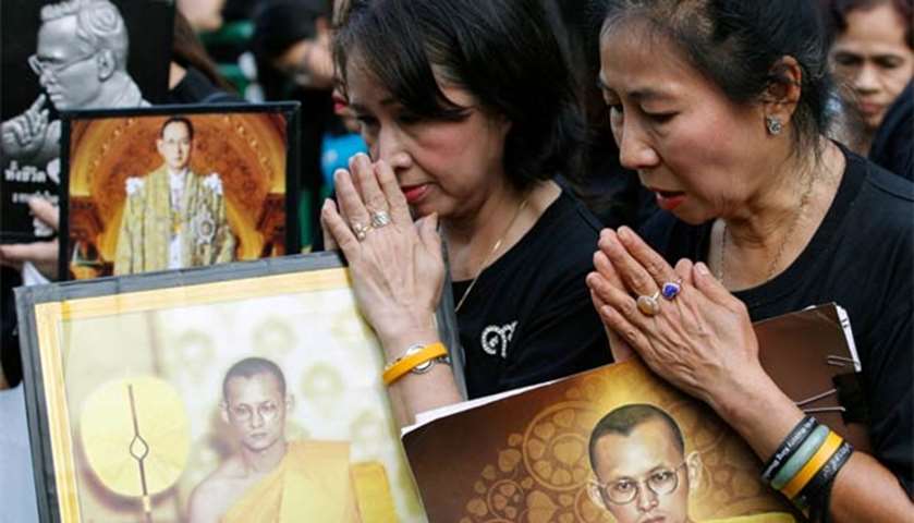 People hold portraits of King Bhumibol Adulyadej as they gather near the Siriraj Hospital in Bangkok