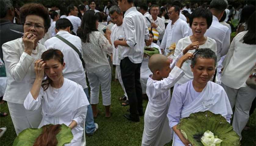 Thai devotees have their hair shaved by their family members during a ceremony in Bangkok on Friday