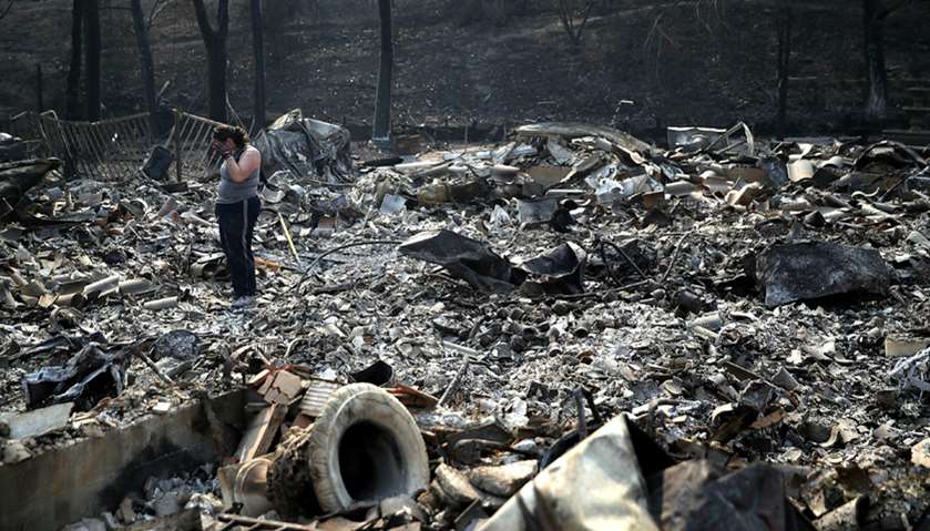 Heather Tiffee wipes her eyes as she looks through the remains of her parents\' home