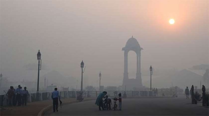 Indians walking near the India Gate monument amid heavy smog in New Delhi on Friday