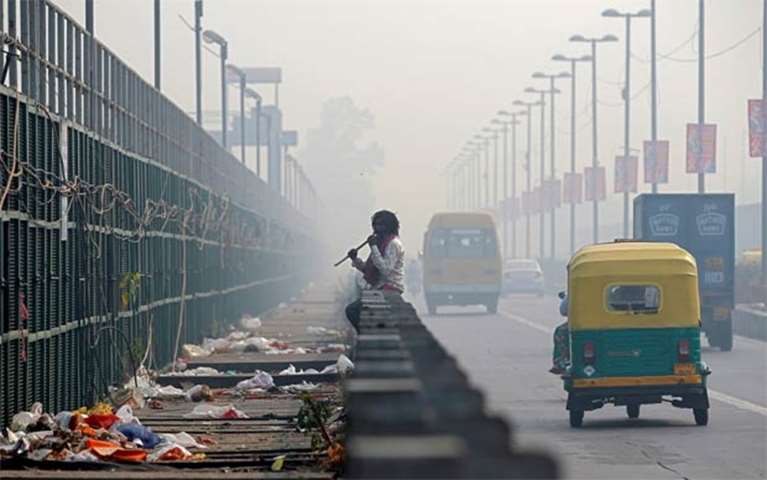 A man chews sugarcane on a bridge during a smoggy morning in New Delhi