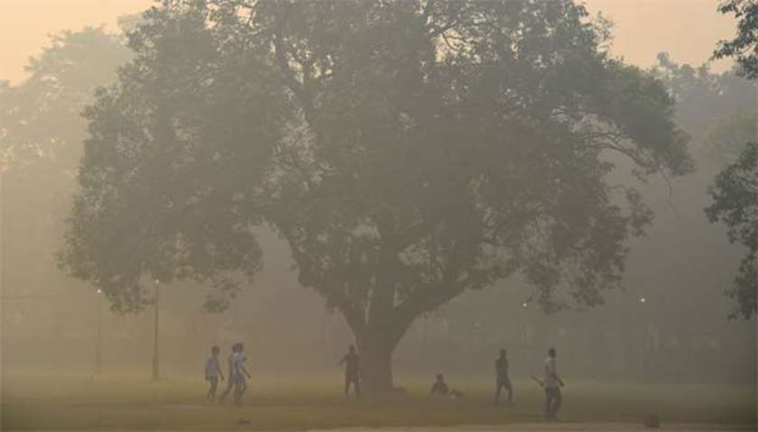 Indians play cricket in smoggy conditions in New Delhi
