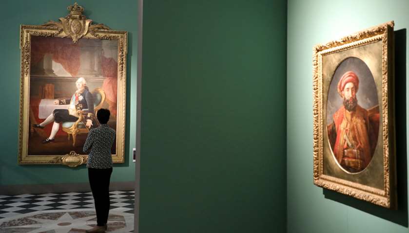 A visitor looks at a portait of French King Louis XVI on display as part of the \"visiteurs de Versai