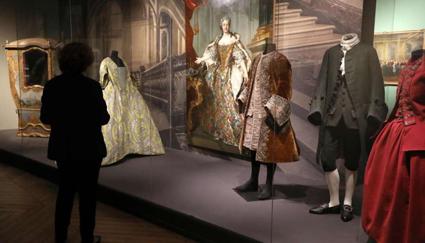 A visitor looks at mannequins with clothing worn at the royal court of French Kings in Versailles