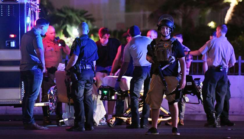 Police officers stand by as medical personnel tend to a person on Tropicana Ave. near Las Vegas Boul