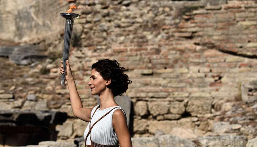 Actress Katerina Lechou acting the high priestess holds a torch with the Olympic flame during a dres