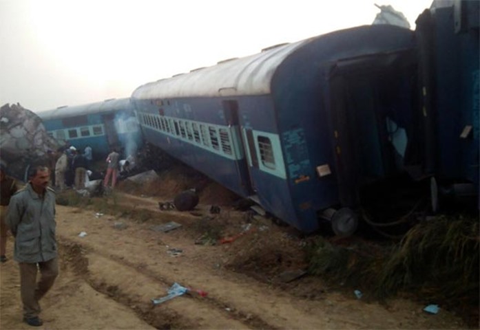 A man walks past the wreckage after an Indian train derailed near Pukhrayan in Kanpur district
