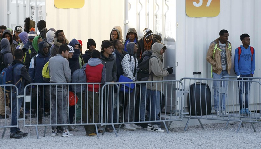 Migrant minors queue to take a bus a the start to their transfer by French authorities