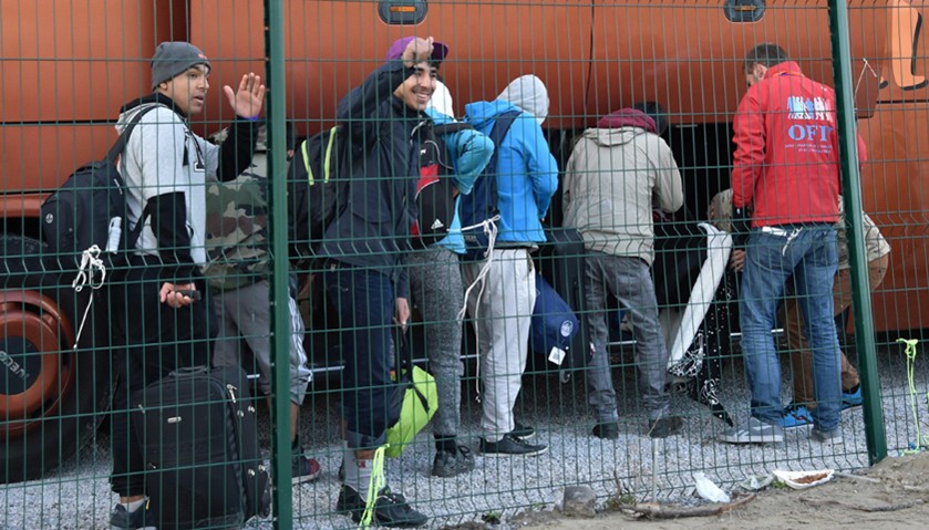 Migrant minors queue to take a bus a the start to their transfer by French authorities