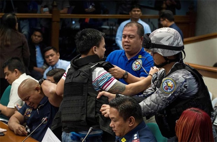 Kerwin Espinosa removes the bullet proof vest during the Senate drug hearing in Manila