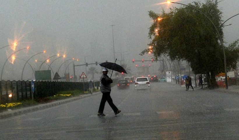 A resident protects himself while crossing a road during the rain