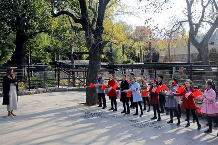 Children holding US and China flags sing for Melania Trump as she visits Beijing Zoo
