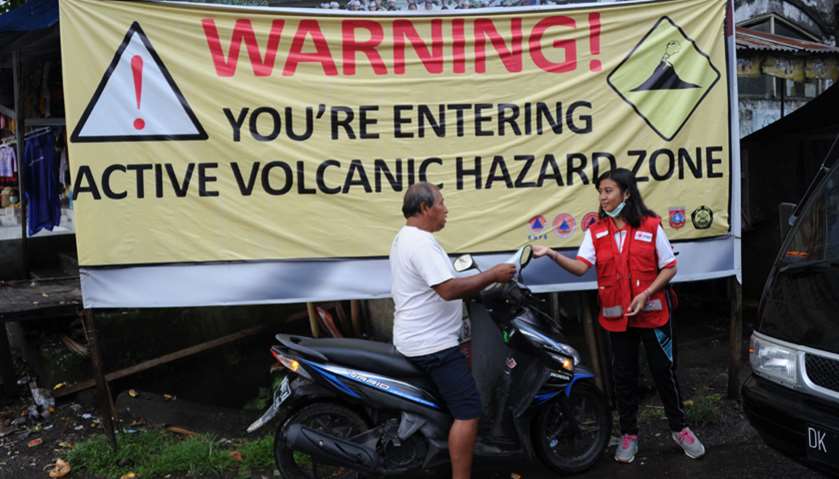 A volunteer hands out a mask to a motorist due to ash in the air from Mt. Agung volcano