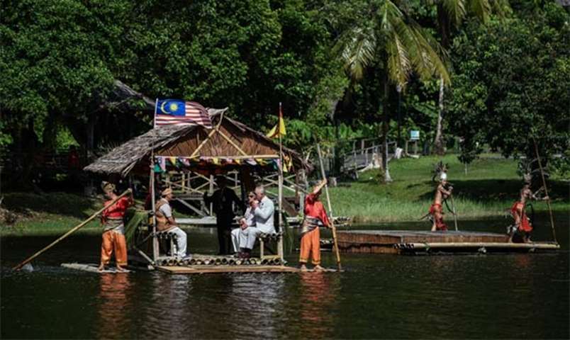 The Prince of Wales and Duchess of Cornwall ride on a raft at the Sarawak Cultural Village