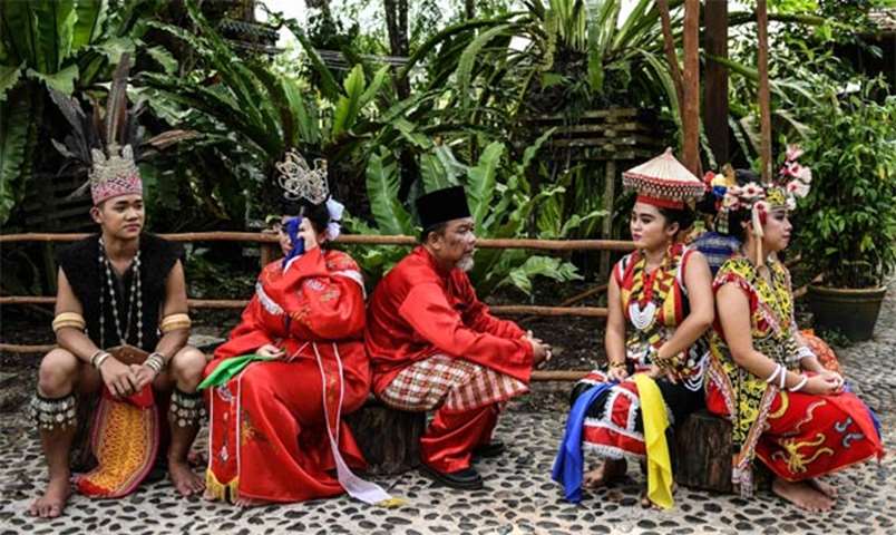 Traditional dancers wait for the British royals to arrive at the Sarawak Cultural Village on Monday