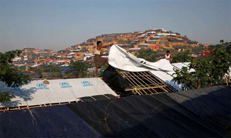 Rohingya refugees cover a newly built temporary shelter with a plastic sheet
