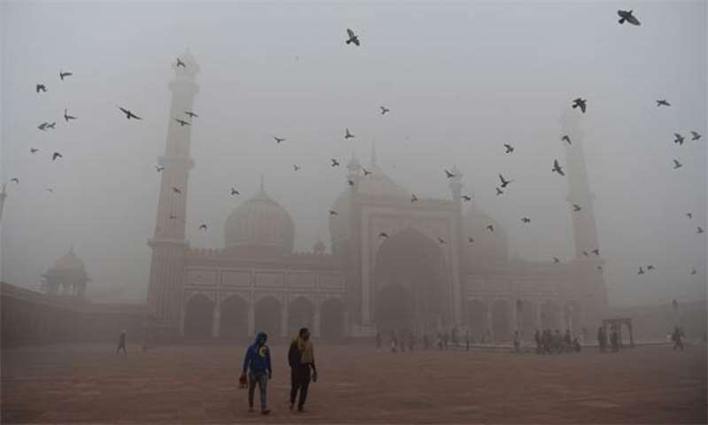 Indian visitors walk through the courtyard of Jama Masjid amid heavy smog in New Delhi on Wednesday