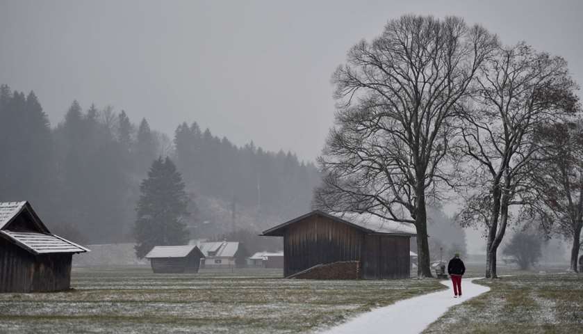 A man walks past barns in Garmisch-Partenkirchen, southern Germany