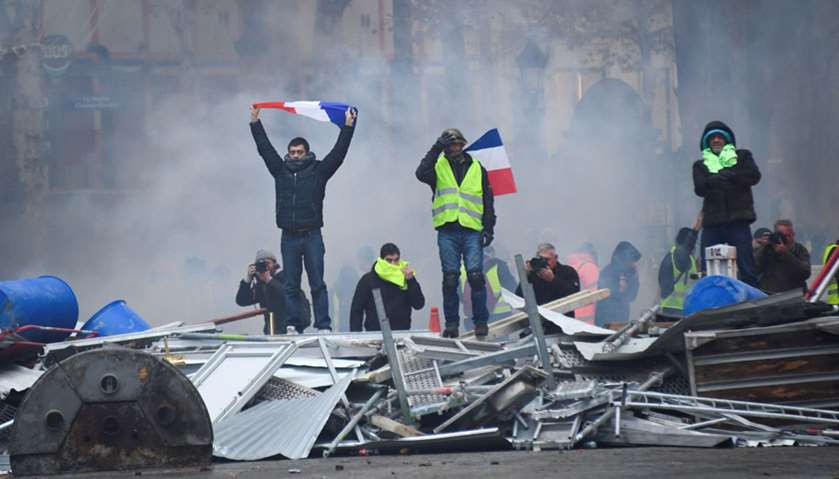 Protestors hold french flags during a protest of Yellow vests against rising oil prices near the Arc