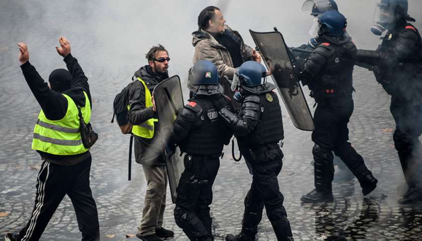 Yellow vests protestors shout slogans as they clash with riot police near the Place de la Concorde i