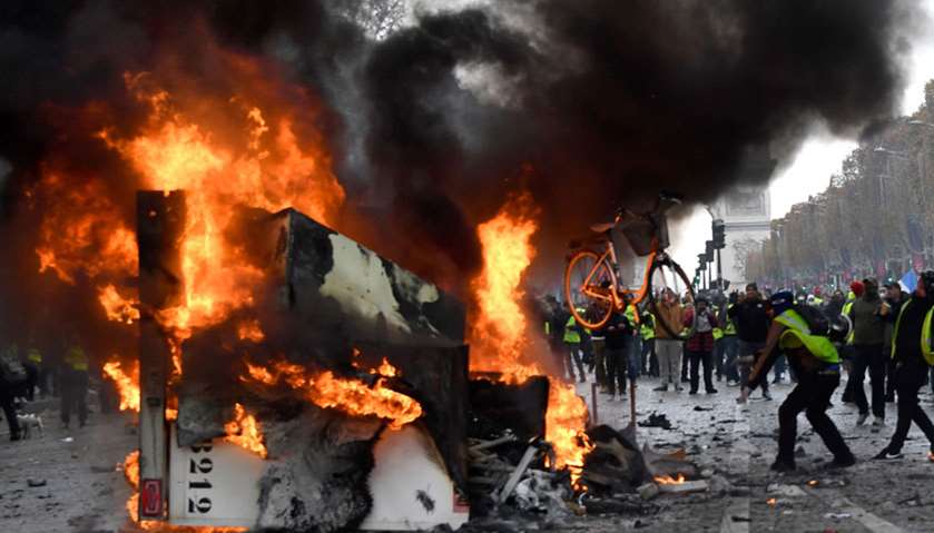 A man throws a bike in a burning truck during a protest of Yellow vests  in Paris