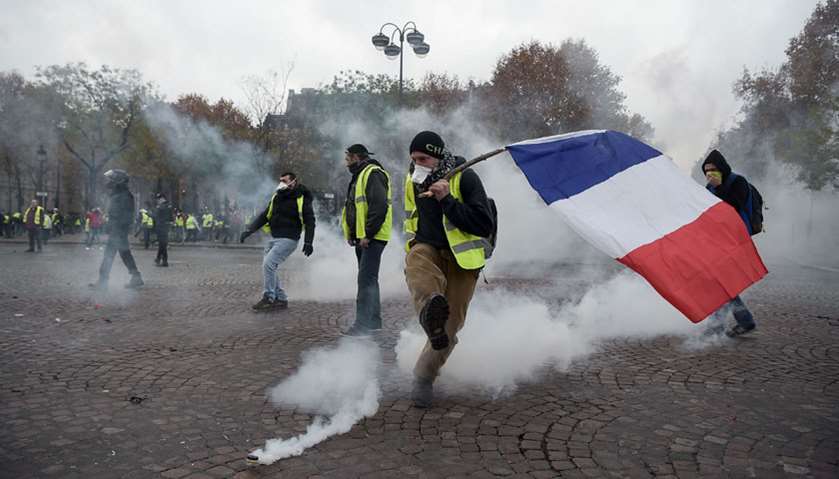 Protestor kicks a tear gas canister on the Champs Elysees in Paris