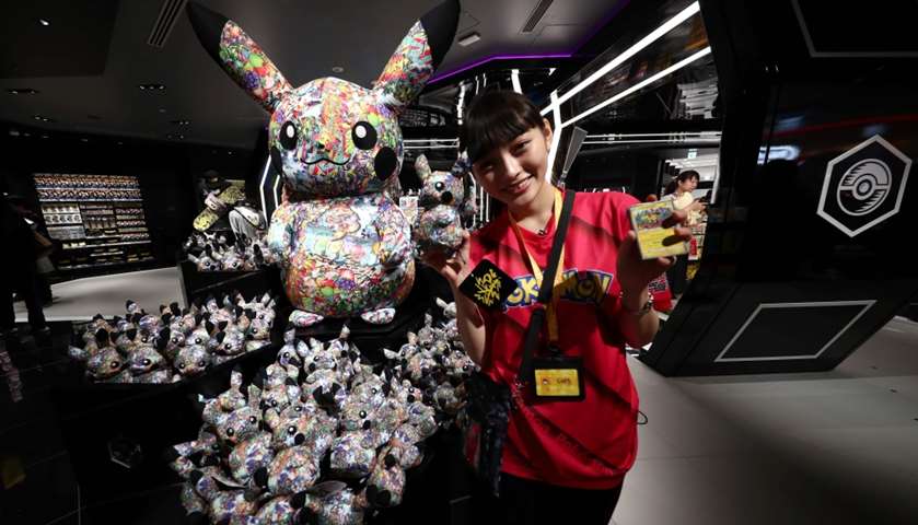 A Pokemon employee poses next to goods of Pokemon video game character Pikachu