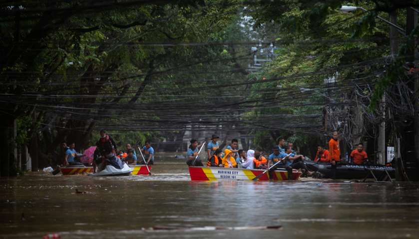 Rescuers onboard boats evacuate residents from a submerged village following Typhoon Vamco, in Manil