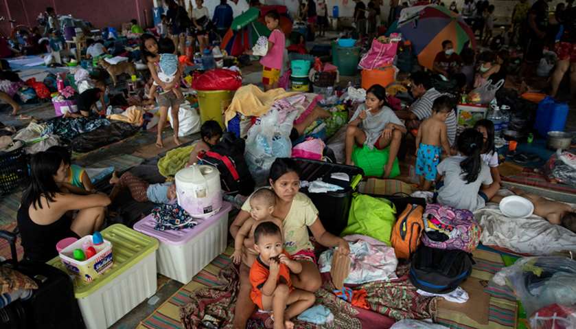 Residents from low-lying communities take shelter in an evacuation center after flooding caused by T
