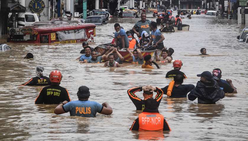 Rescuers pull a rubber boat carrying residents through a flooded street after Typhoon Vamco