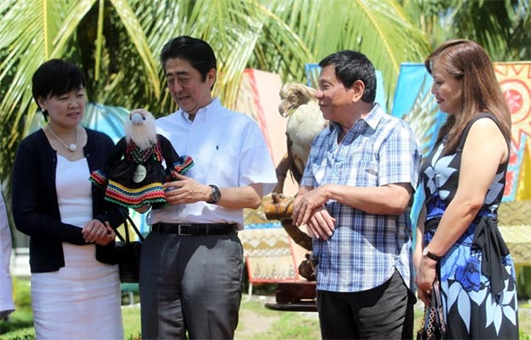 Shinzo Abe holds a stuffed toy as his wife, and Rodrigo Duterte and his partner look on