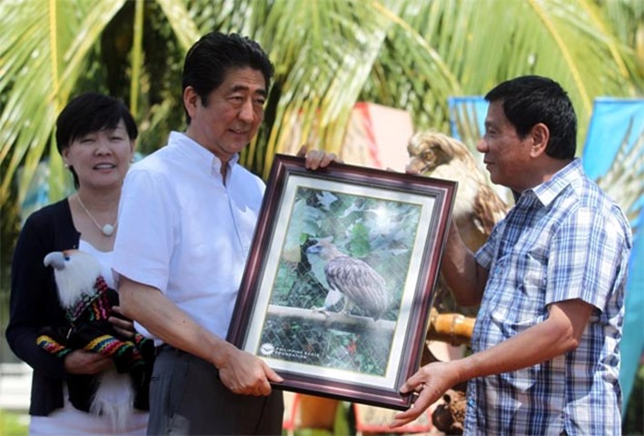 Rodrigo Duterte hands over a framed photograph of a Philippine Eagle to the Japanese PM on Friday