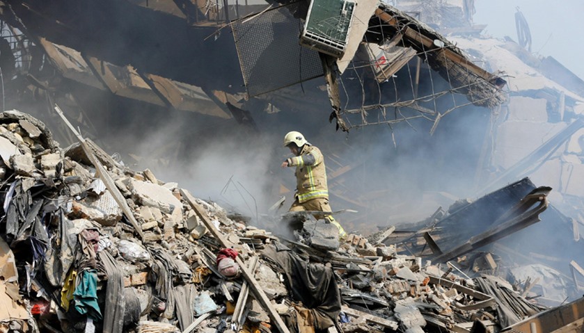 An Iranian firefighters walks amidst the debris of Iran\'s oldest high-rise, the 15-storey Plasco bui
