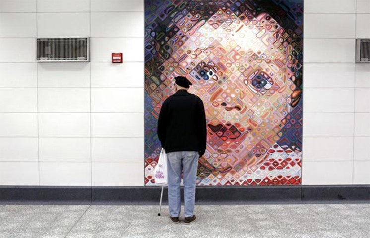 A man checks out a tile mosaic by Chuck Close decorating the 86th St. Q train station