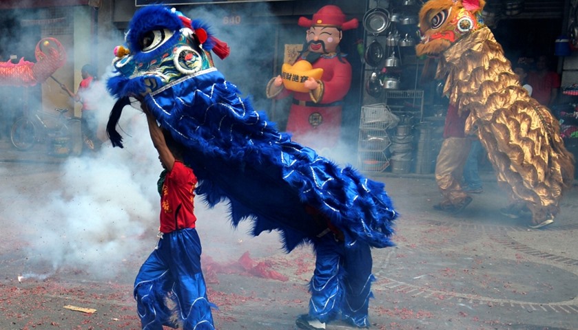 Revellers perform a lion dance amidst exploding firecrackers