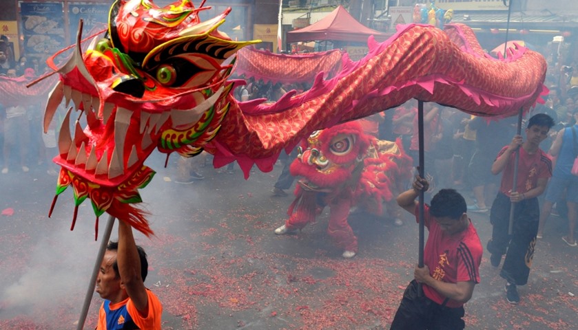 Revellers perform a dragon dance among smoke caused by firecrackers