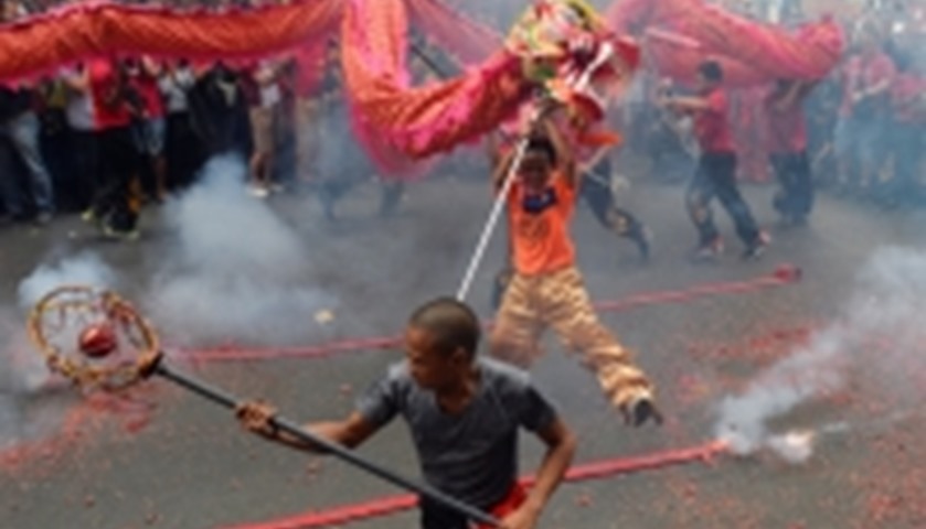 Revellers perform a dragon dance next to firecrackers