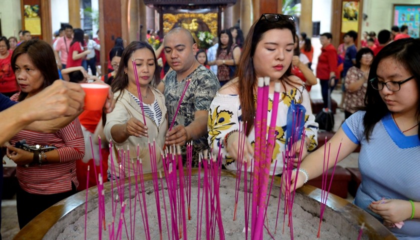 Members of the Chinese community light incense sticks as they offer prayers in Seng Guan temple