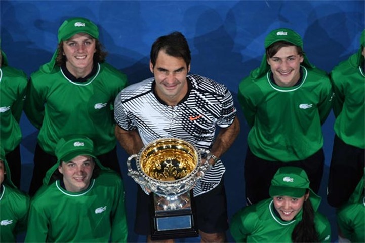 Roger Federer holds the winner\'s trophy as he poses with ball kids at the awards ceremony